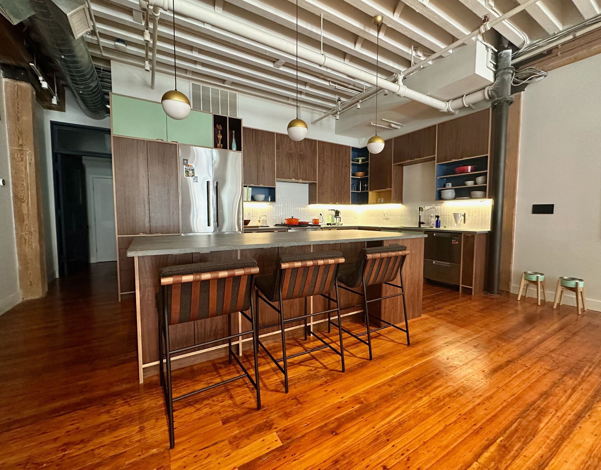 A kitchen with a large island and three bar stools