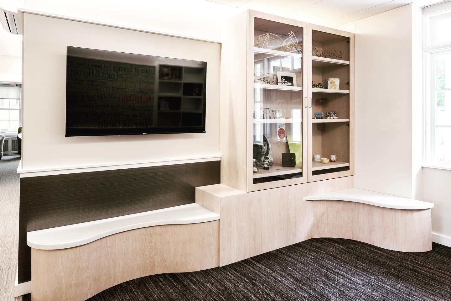 A living room with a curved bench and a flat screen tv on the wall.