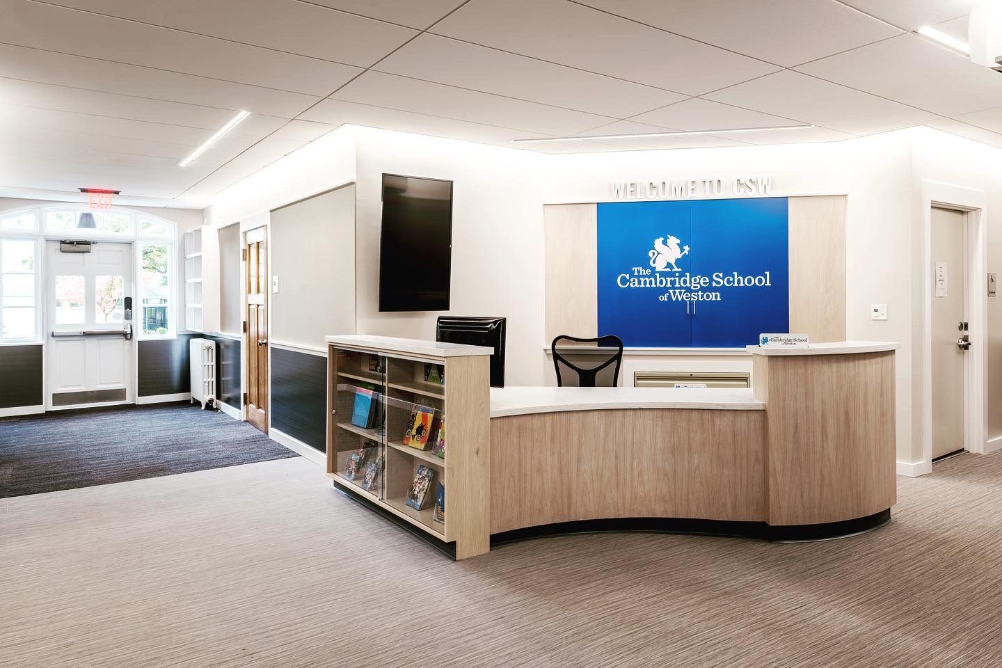 A reception area in a school with a blue sign on the wall.