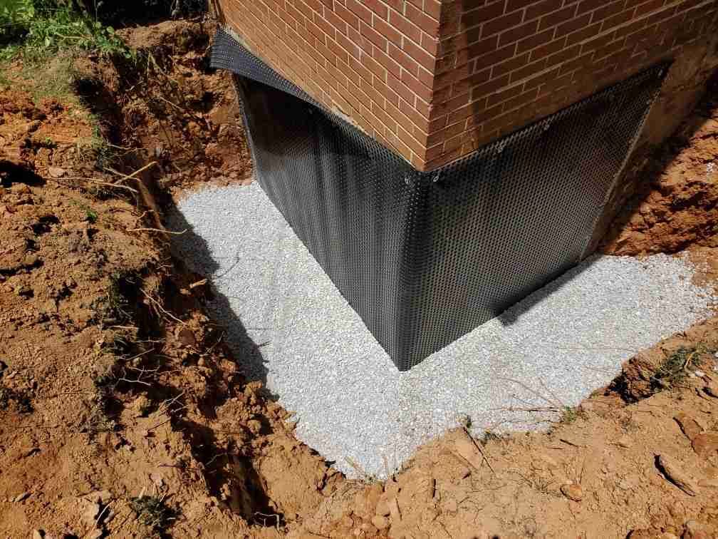 A brick building with a foundation being built in the dirt.