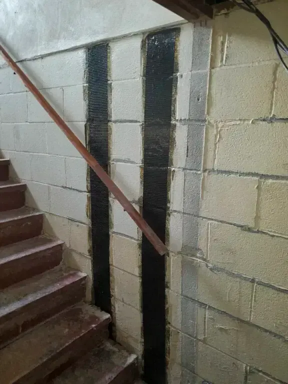 A staircase with a wooden railing and a brick wall