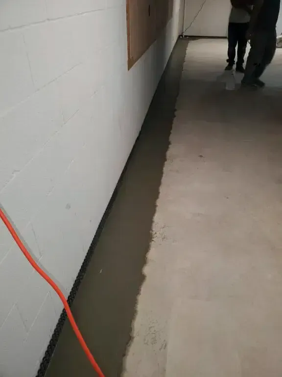 A person is standing next to a wall in a hallway.