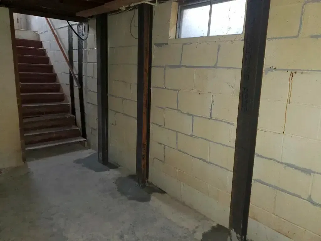 A basement with a staircase and brick walls.