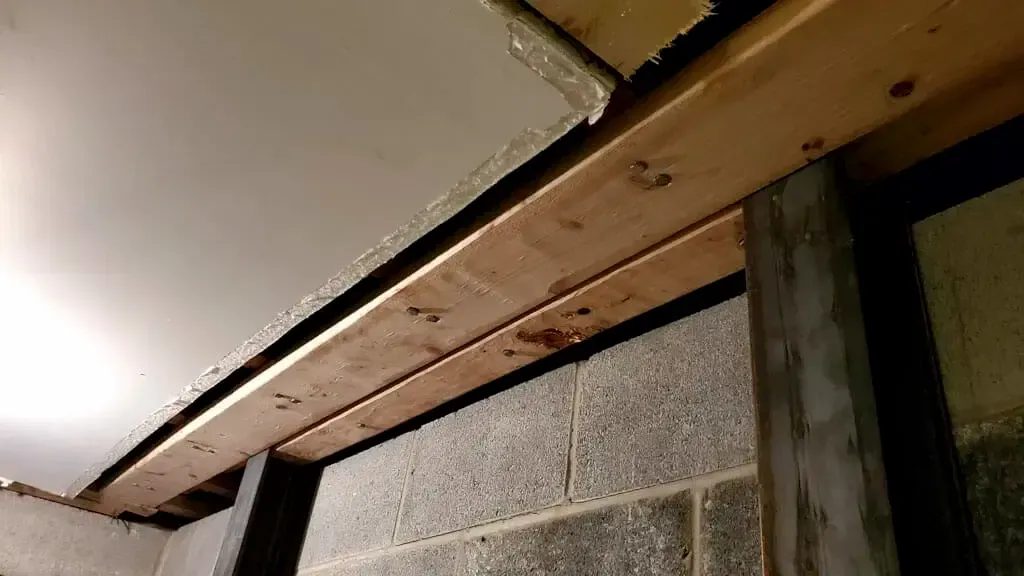 A wooden beam is sitting on top of a brick wall.