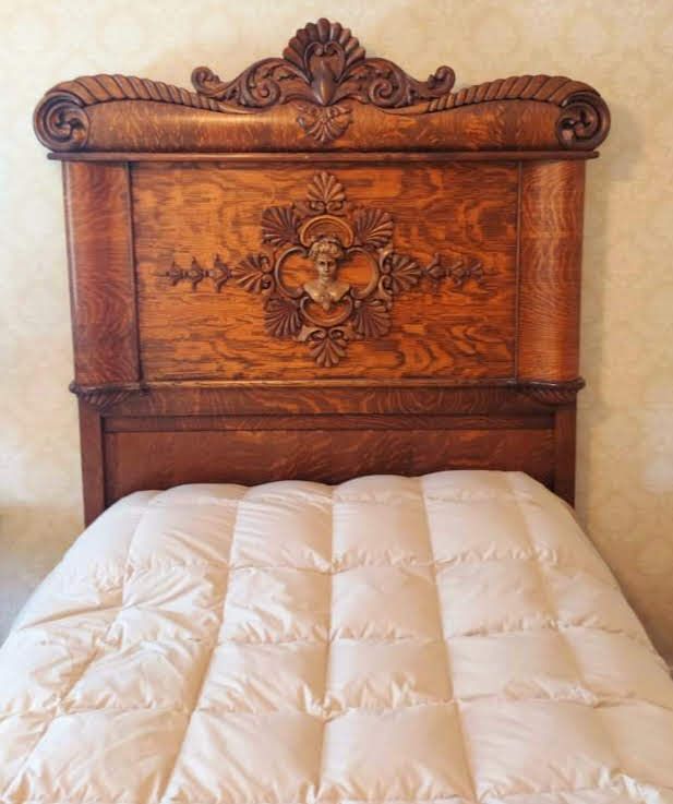A bed with a wooden headboard and a white comforter