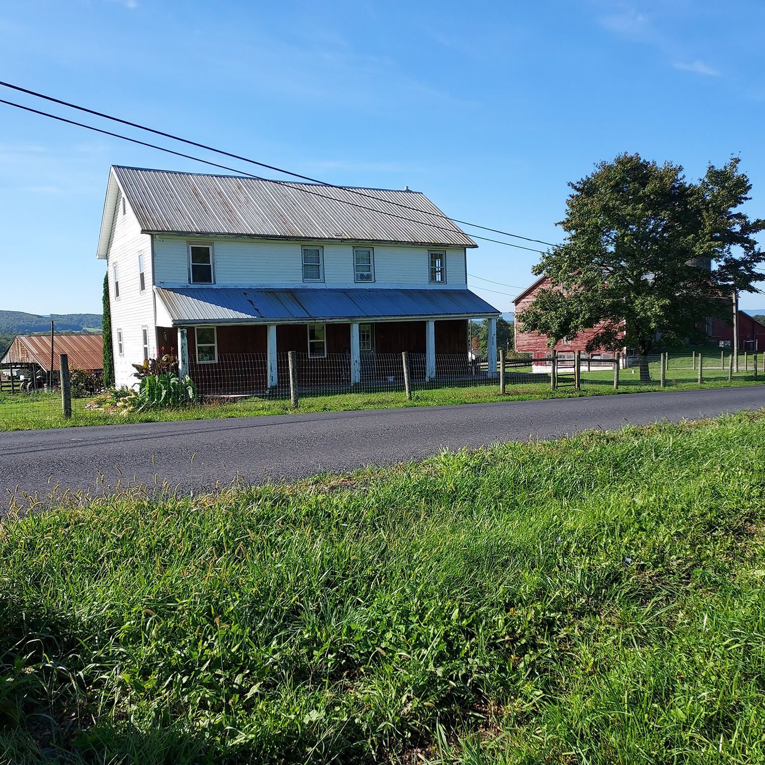 A white house with a porch on the side of a road