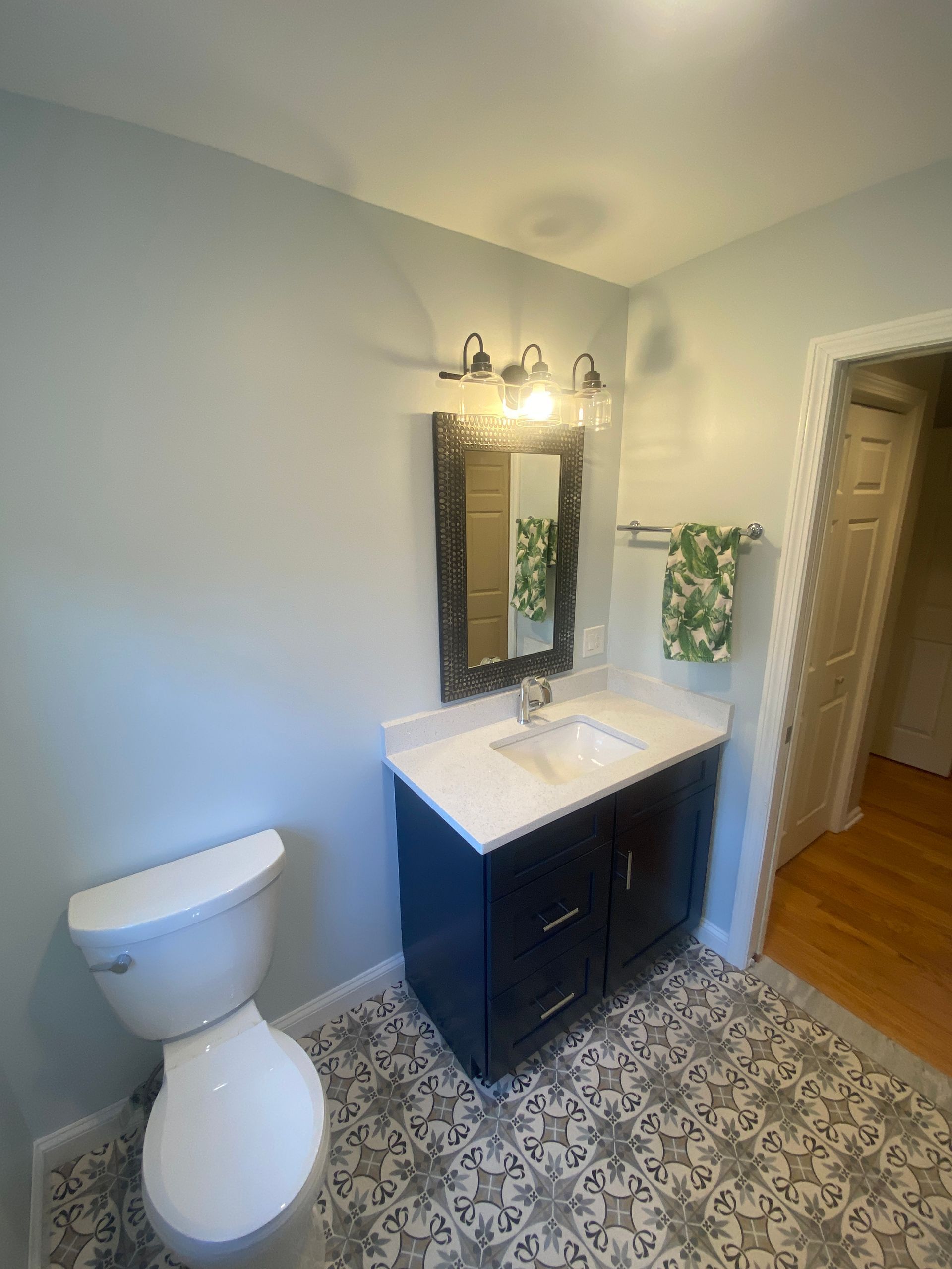 A bathroom with a toilet , sink and mirror.