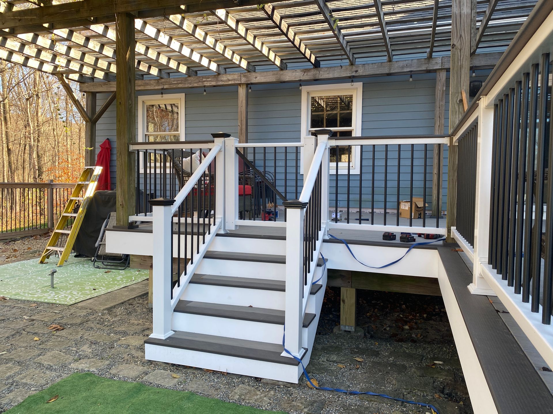 A deck with stairs and a pergola on top of it.