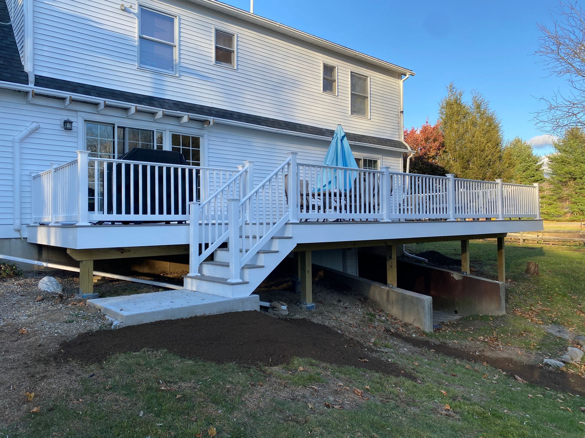 A white house with a large deck and stairs in front of it.