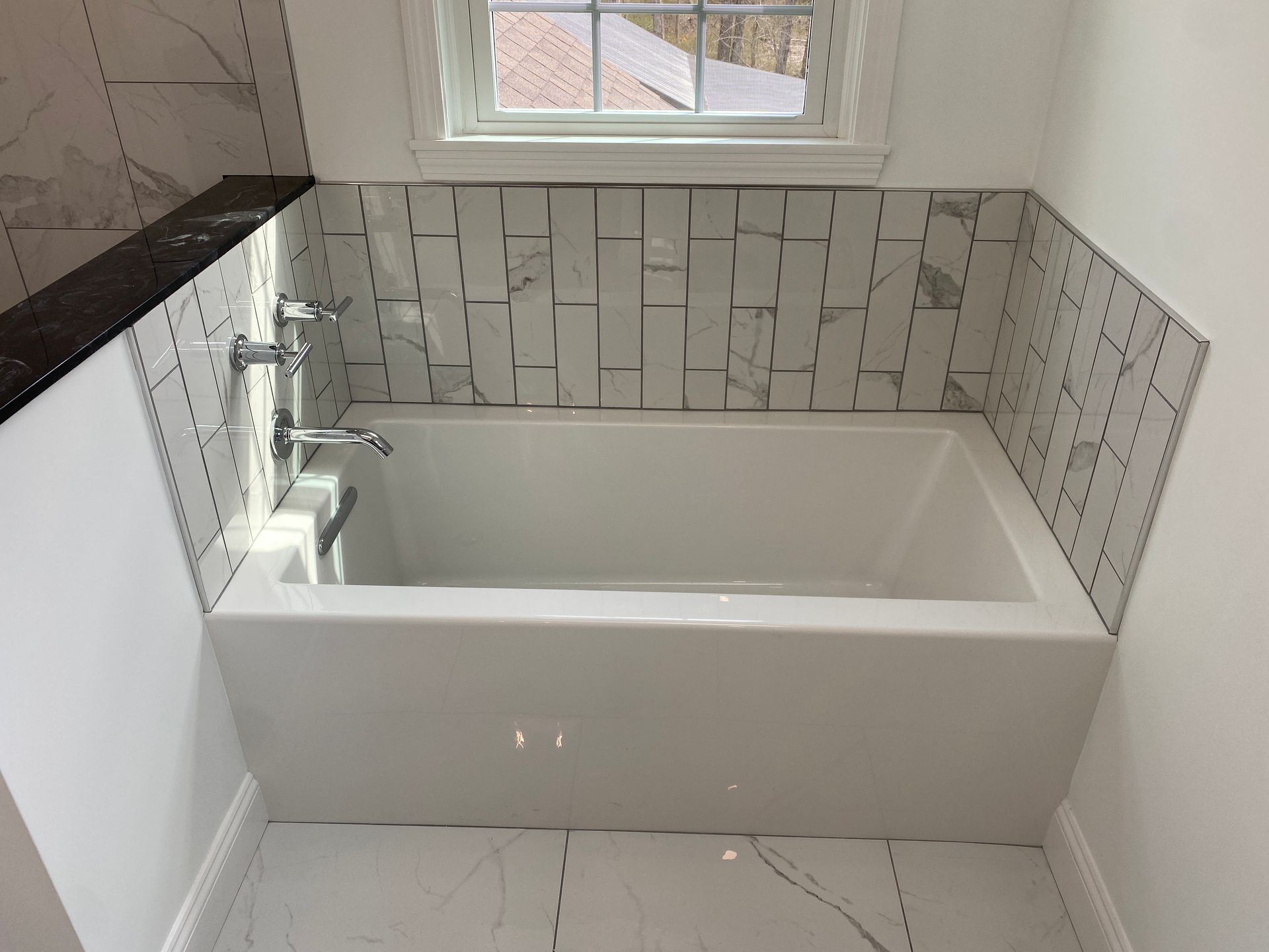 A bathtub in a bathroom next to a window