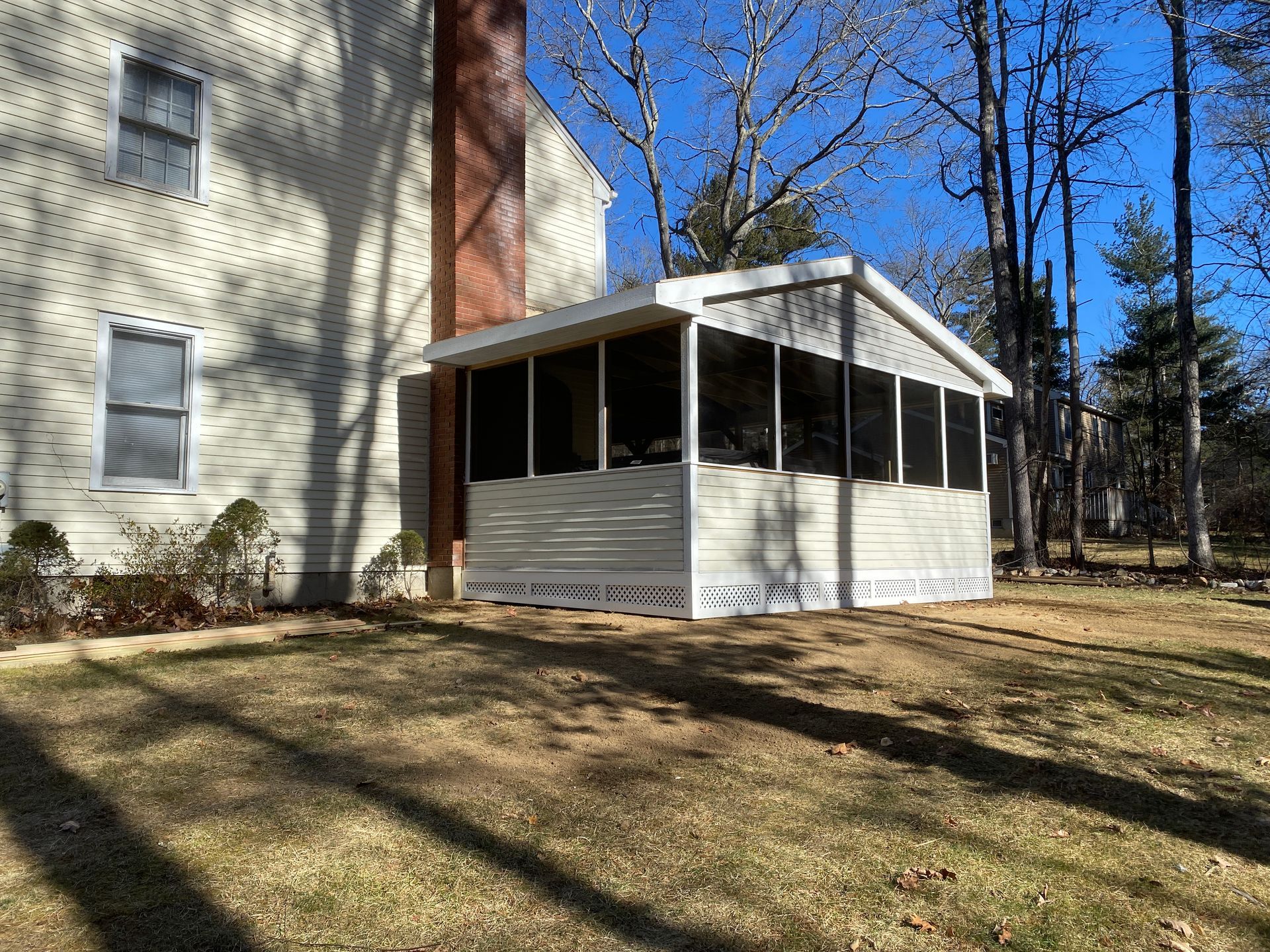 A screened in porch is in the backyard of a house.