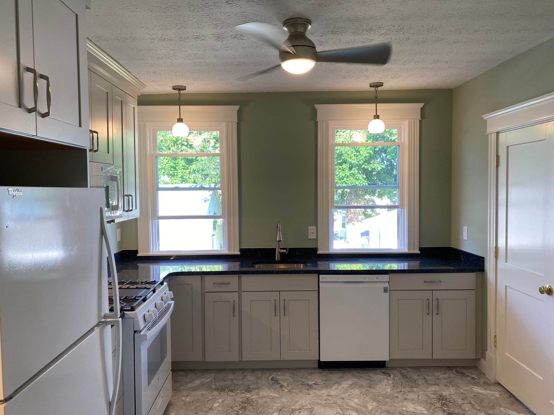 A kitchen with white cabinets and a ceiling fan