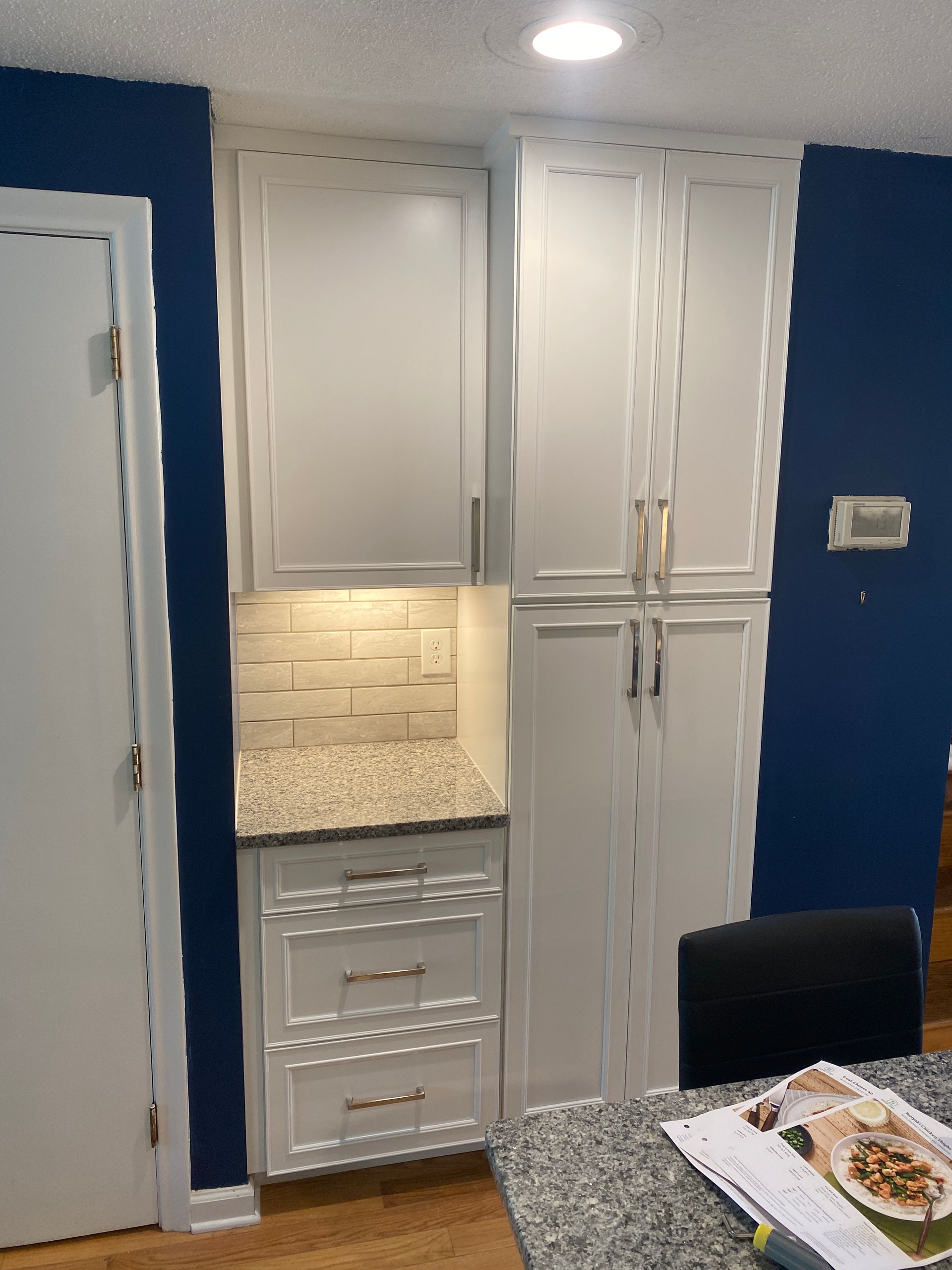 A kitchen with blue walls and white cabinets