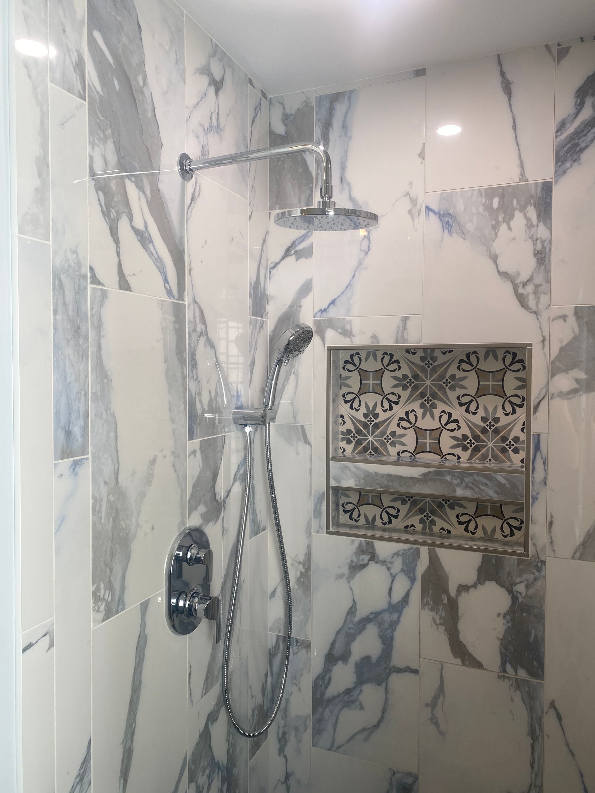 A bathroom with marble tiles and a shower head