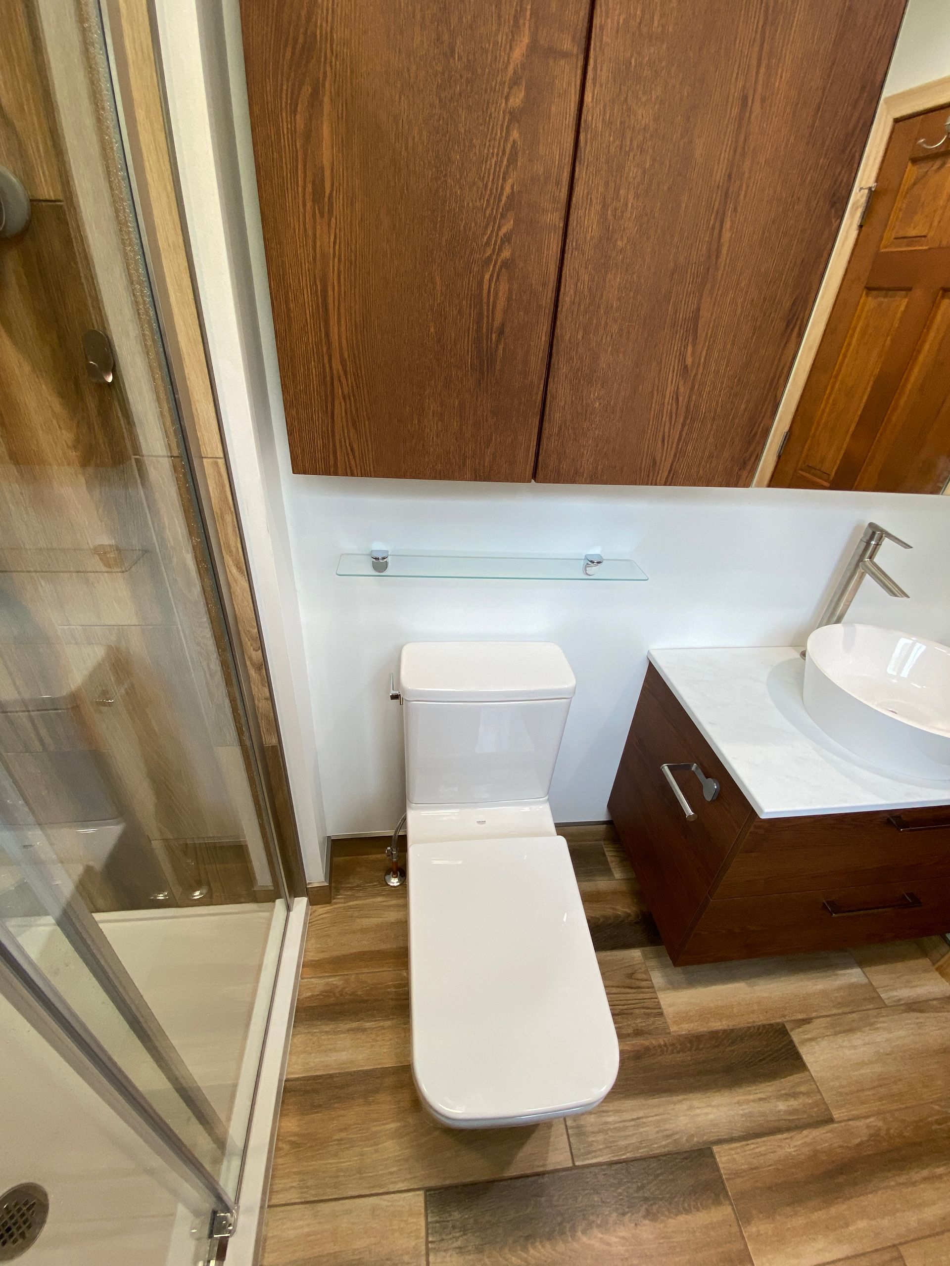 A bathroom with a toilet , sink and shower.