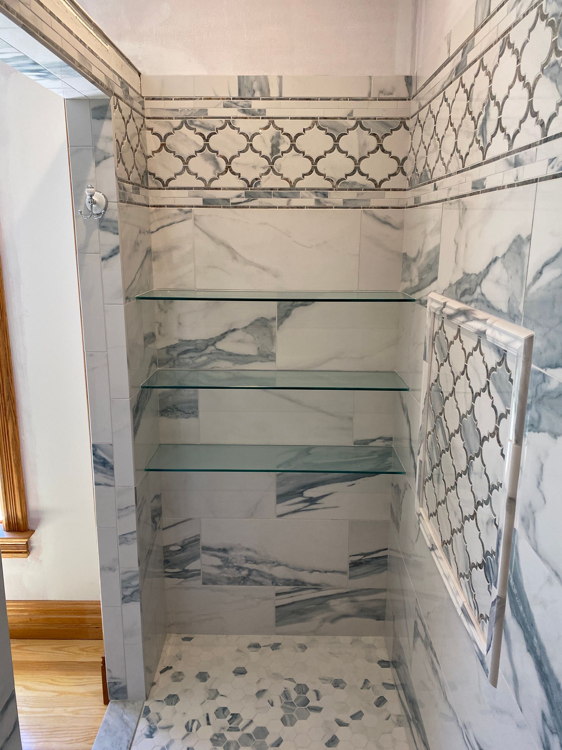 A bathroom with marble tiles and glass shelves