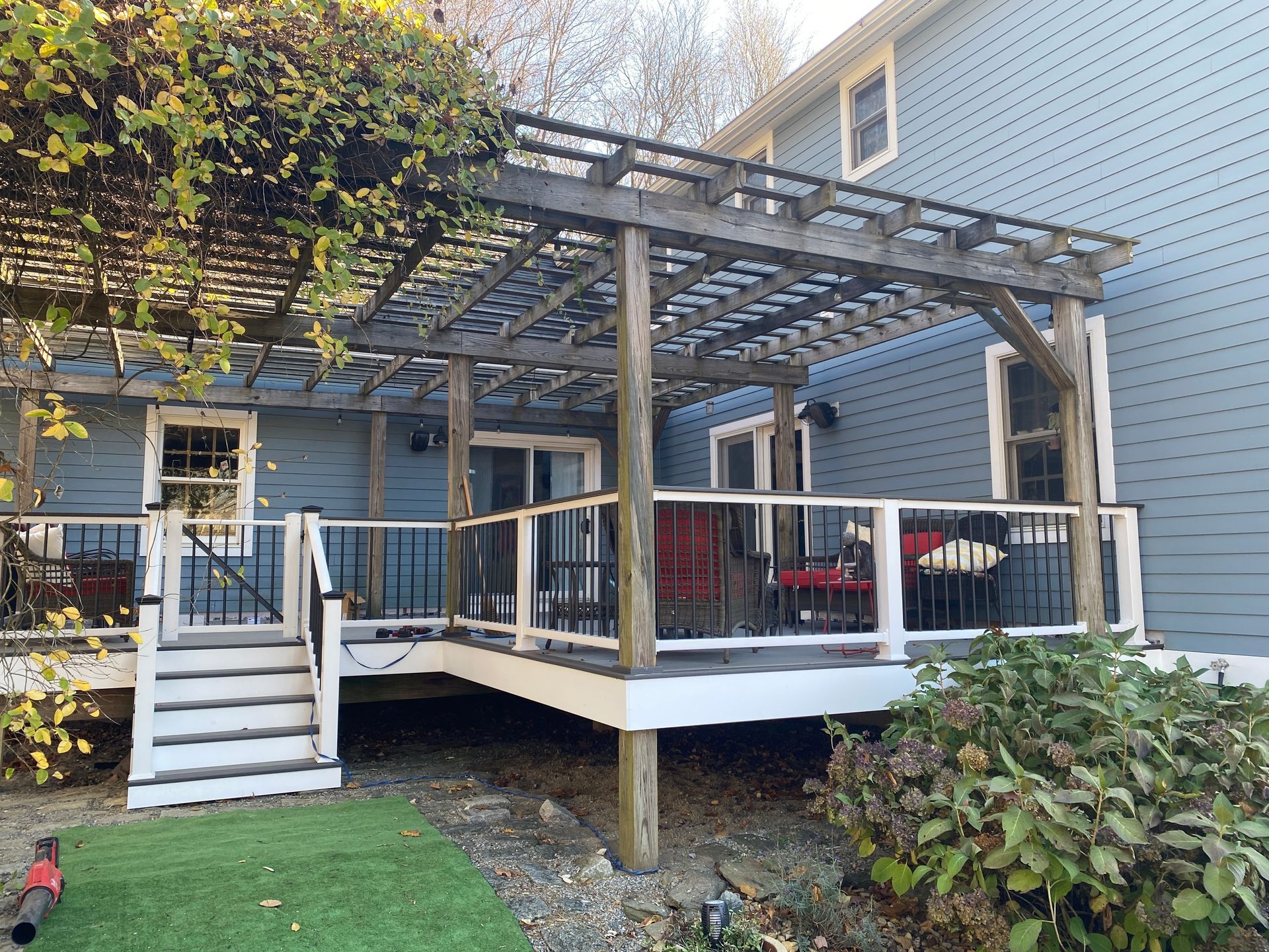 A blue house with a wooden deck and a pergola.