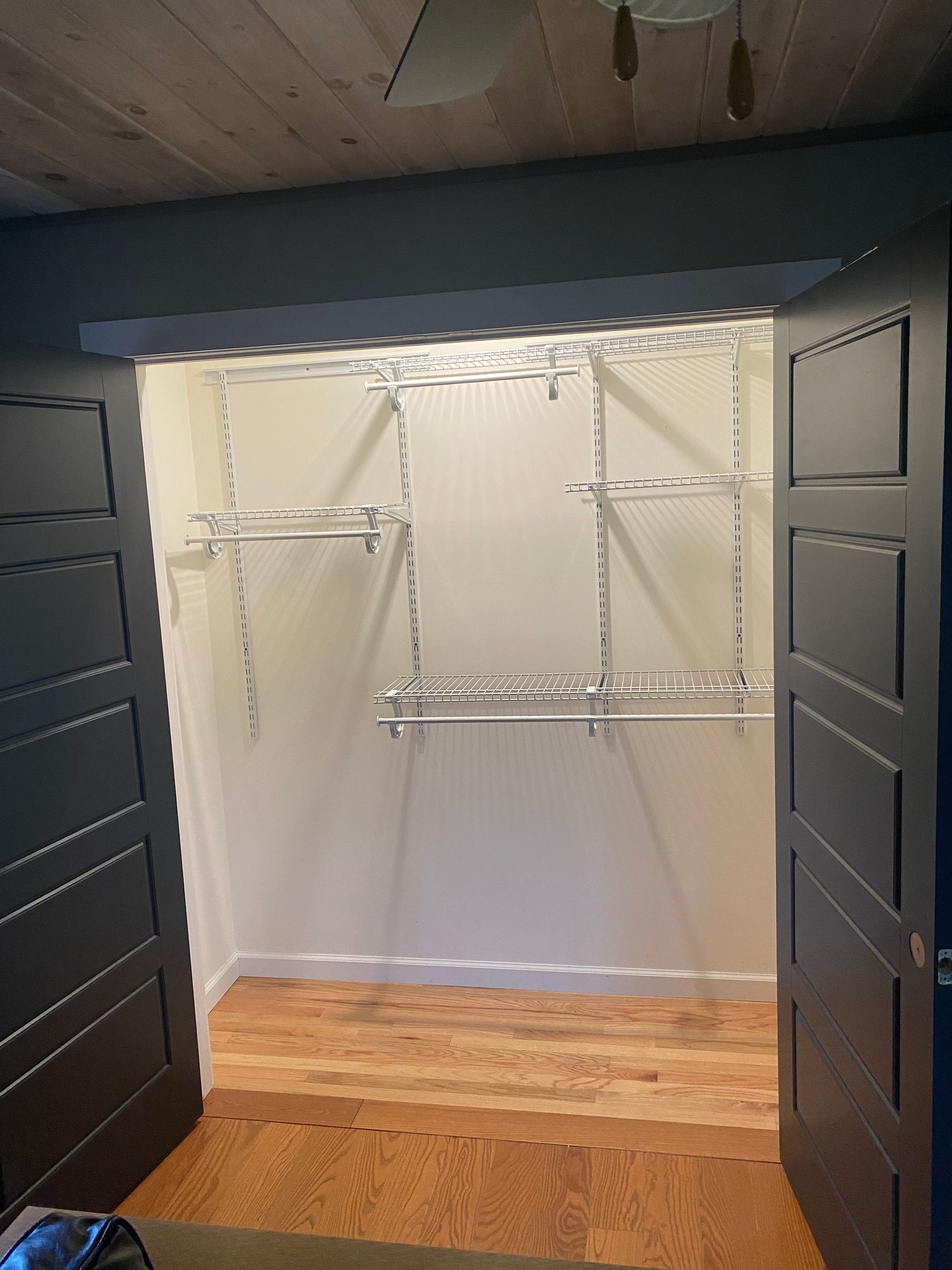 A walk in closet with wooden floors and shelves.