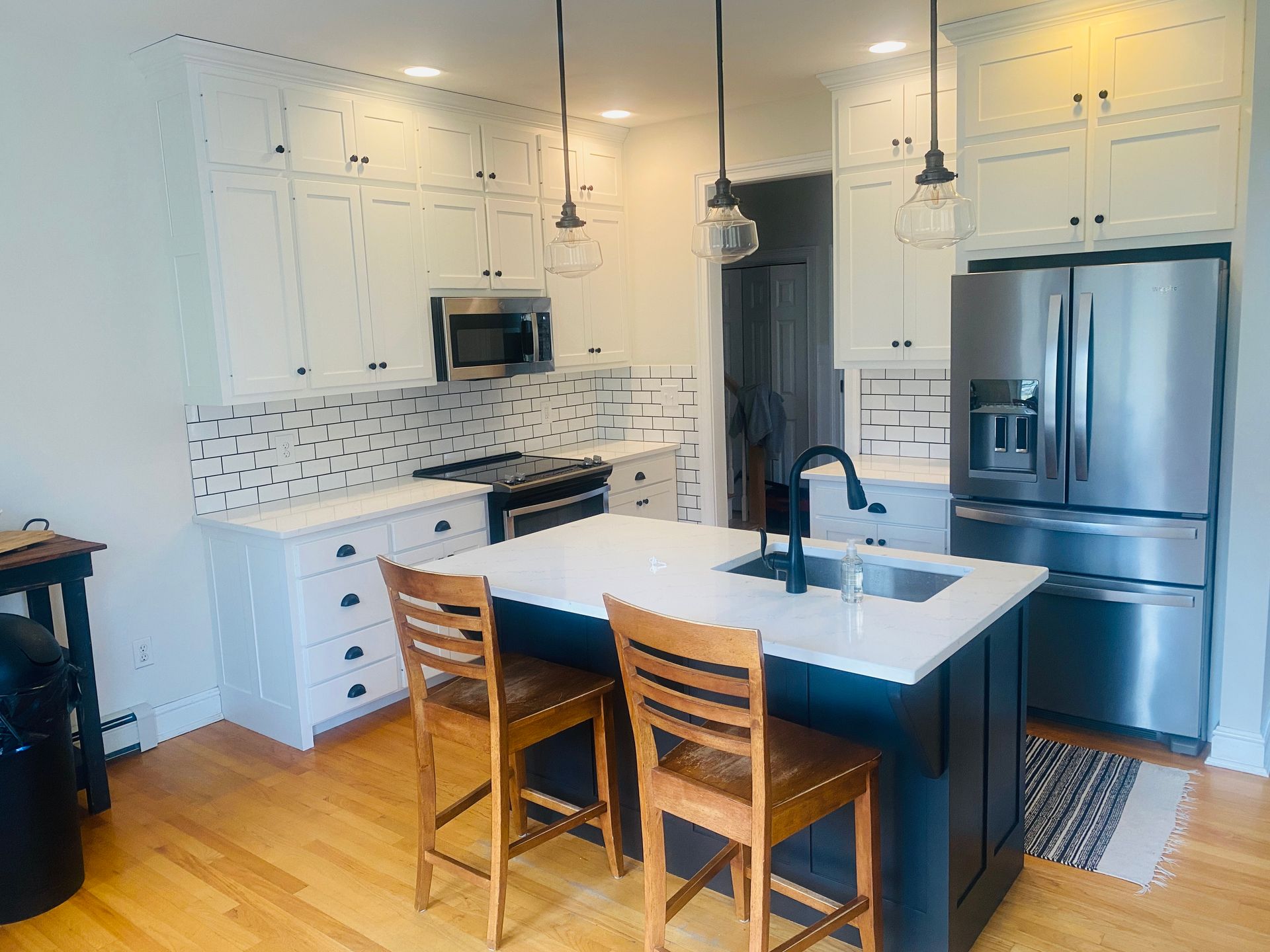 A kitchen with white cabinets , stainless steel appliances and a large island.