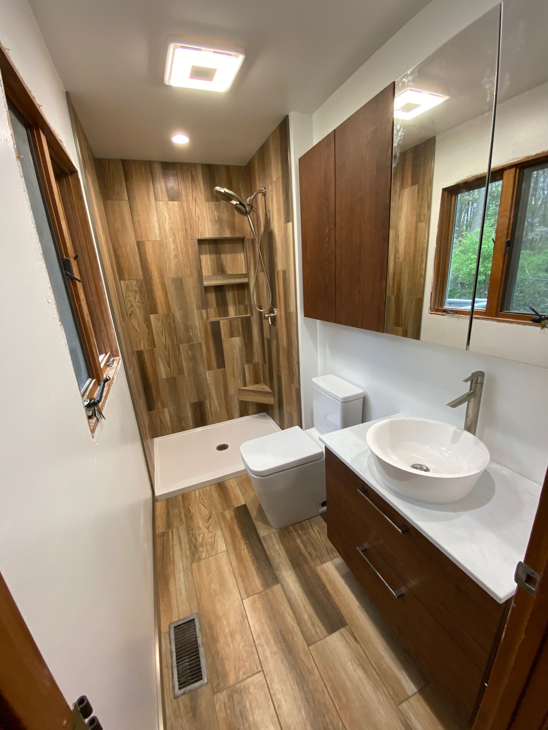 A bathroom with a sink , toilet , shower and mirror.