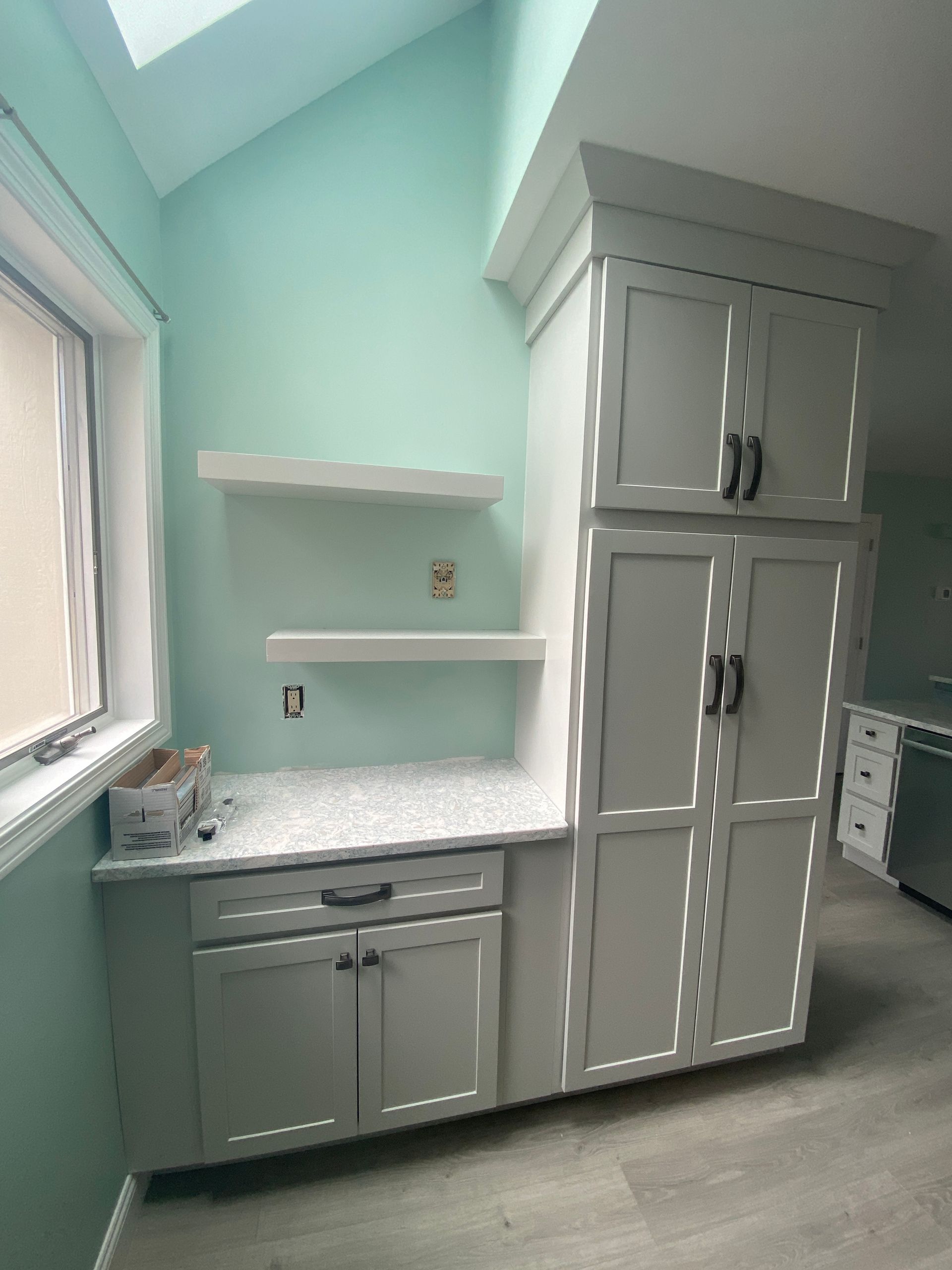 A kitchen with white cabinets and a window.