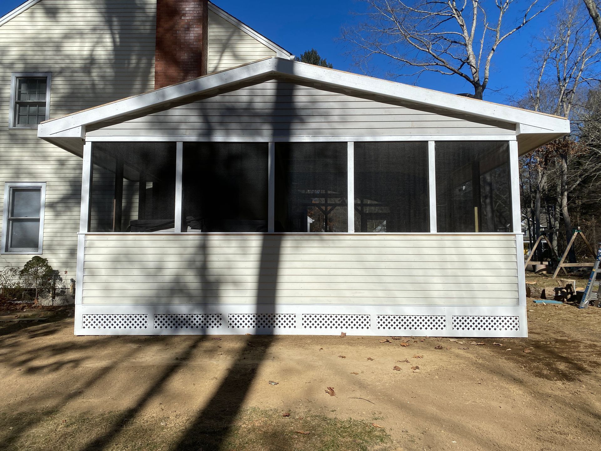A screened in porch is sitting in front of a house.