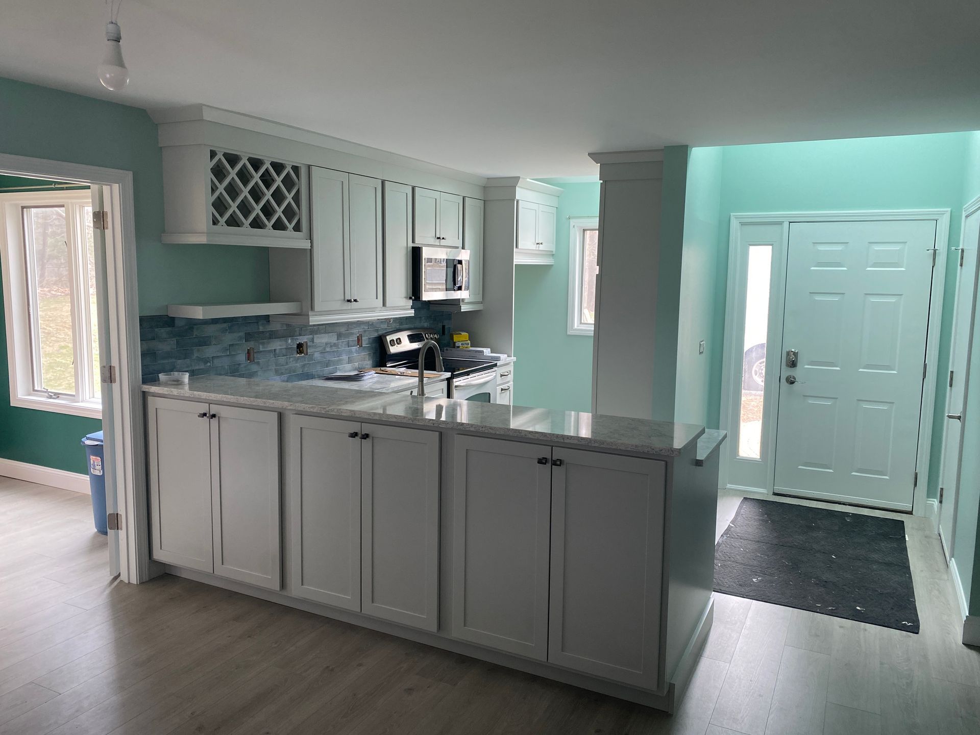 A kitchen with white cabinets , a microwave , a sink , and a door.