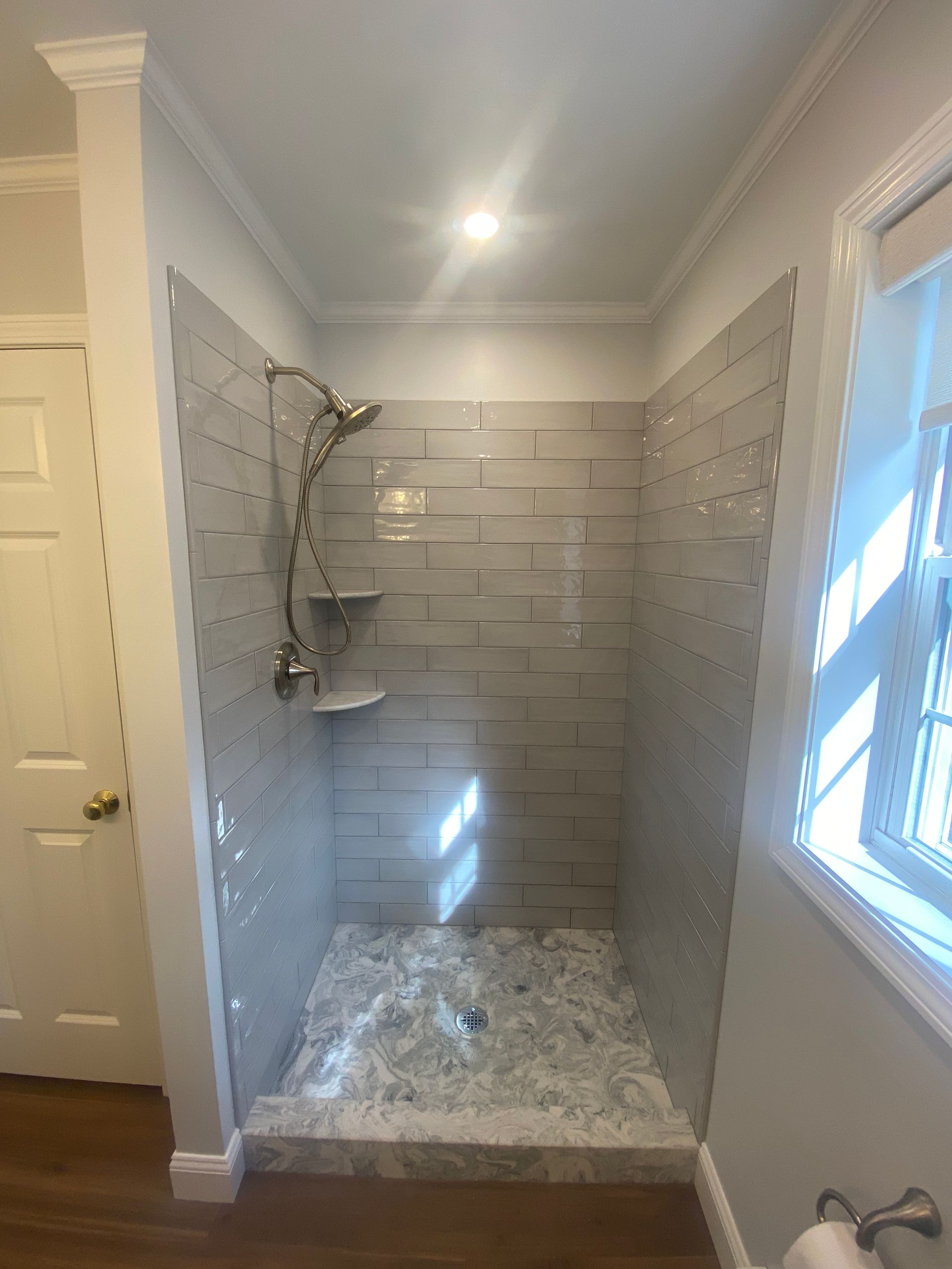 A bathroom with a walk in shower and a window.