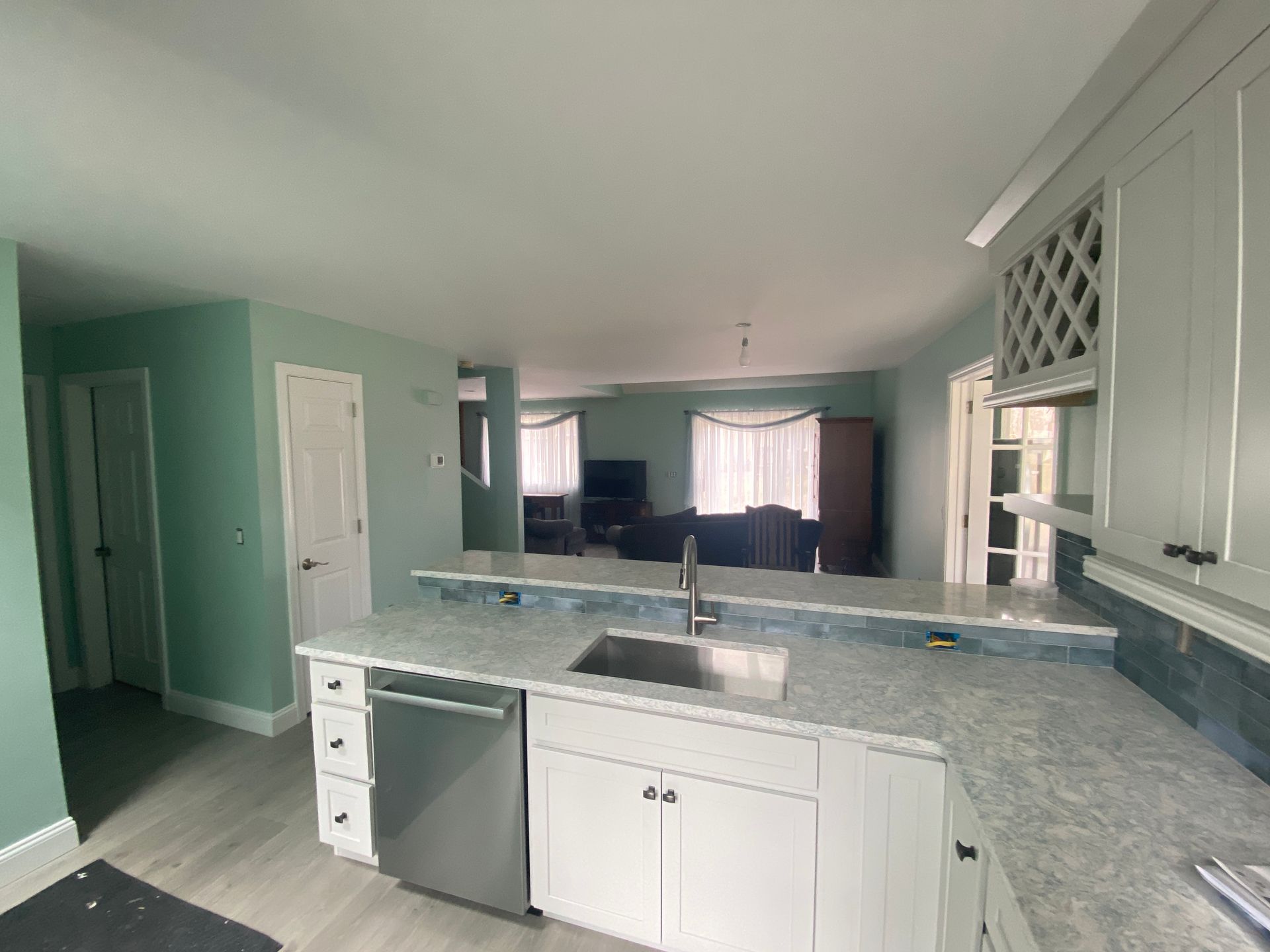 A kitchen with white cabinets , a sink , and a dishwasher.