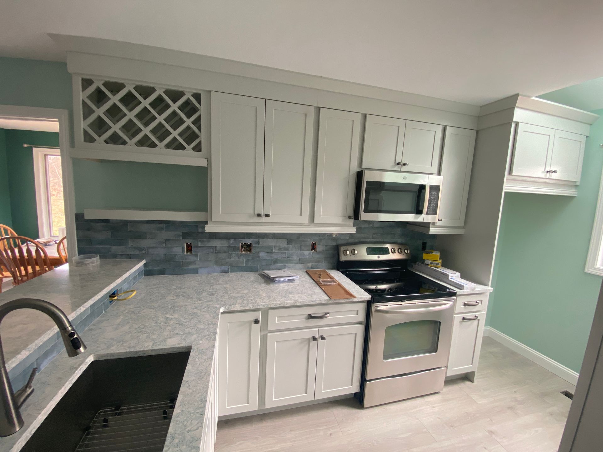 A kitchen with white cabinets , stainless steel appliances , a sink , and a stove.