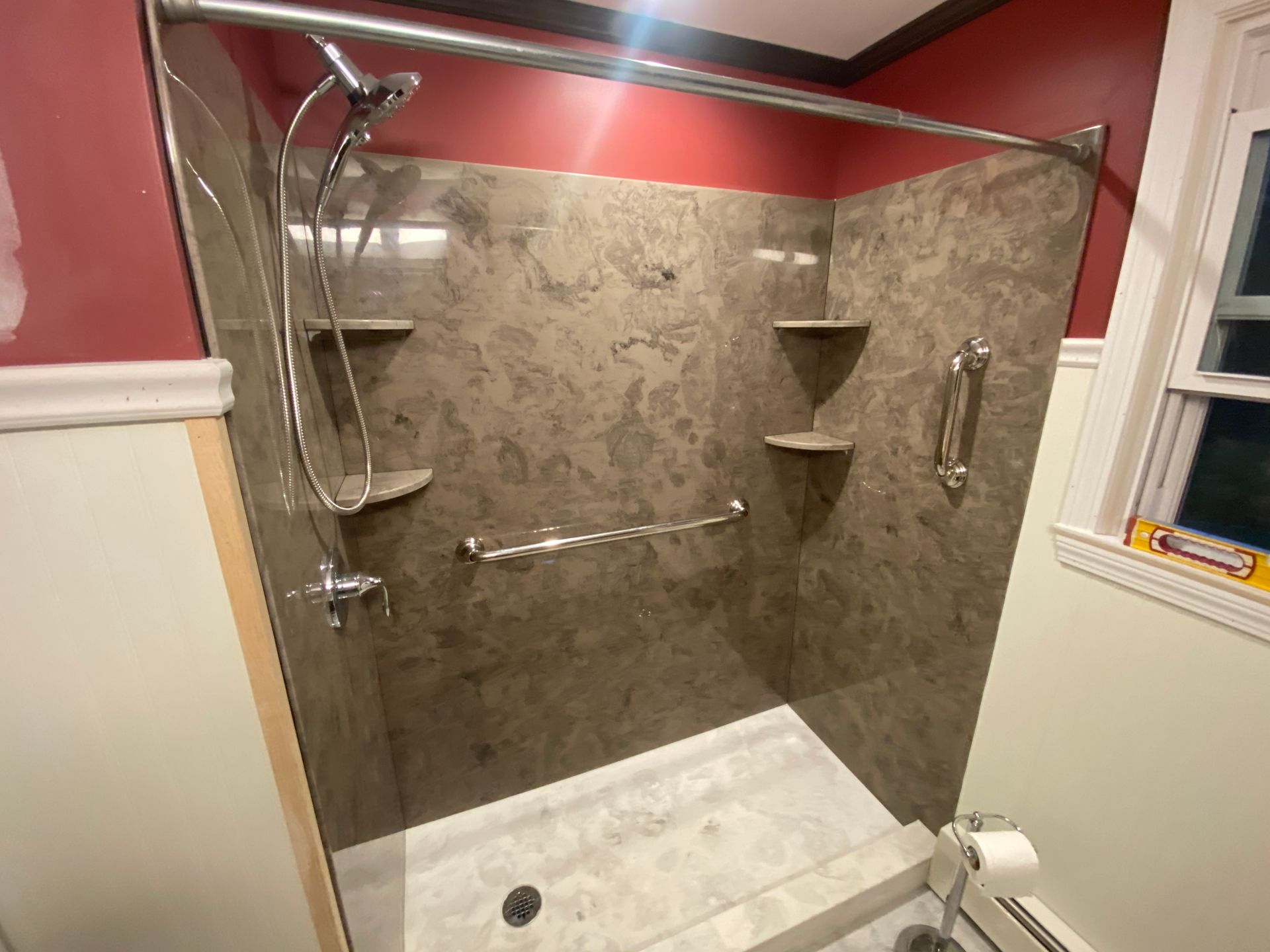 A bathroom with a walk in shower and a window.