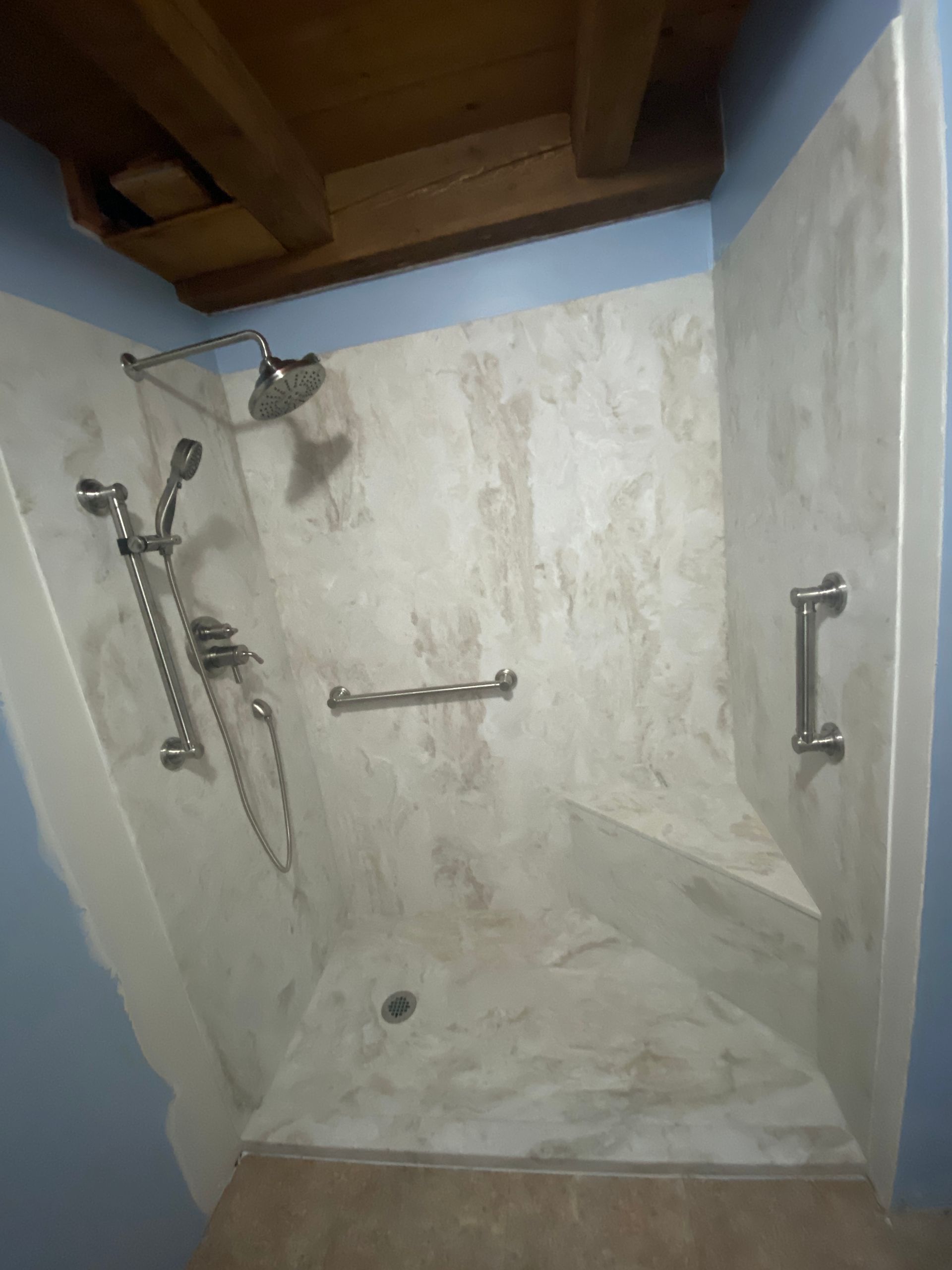 A walk in shower with a hand rail and a shower head