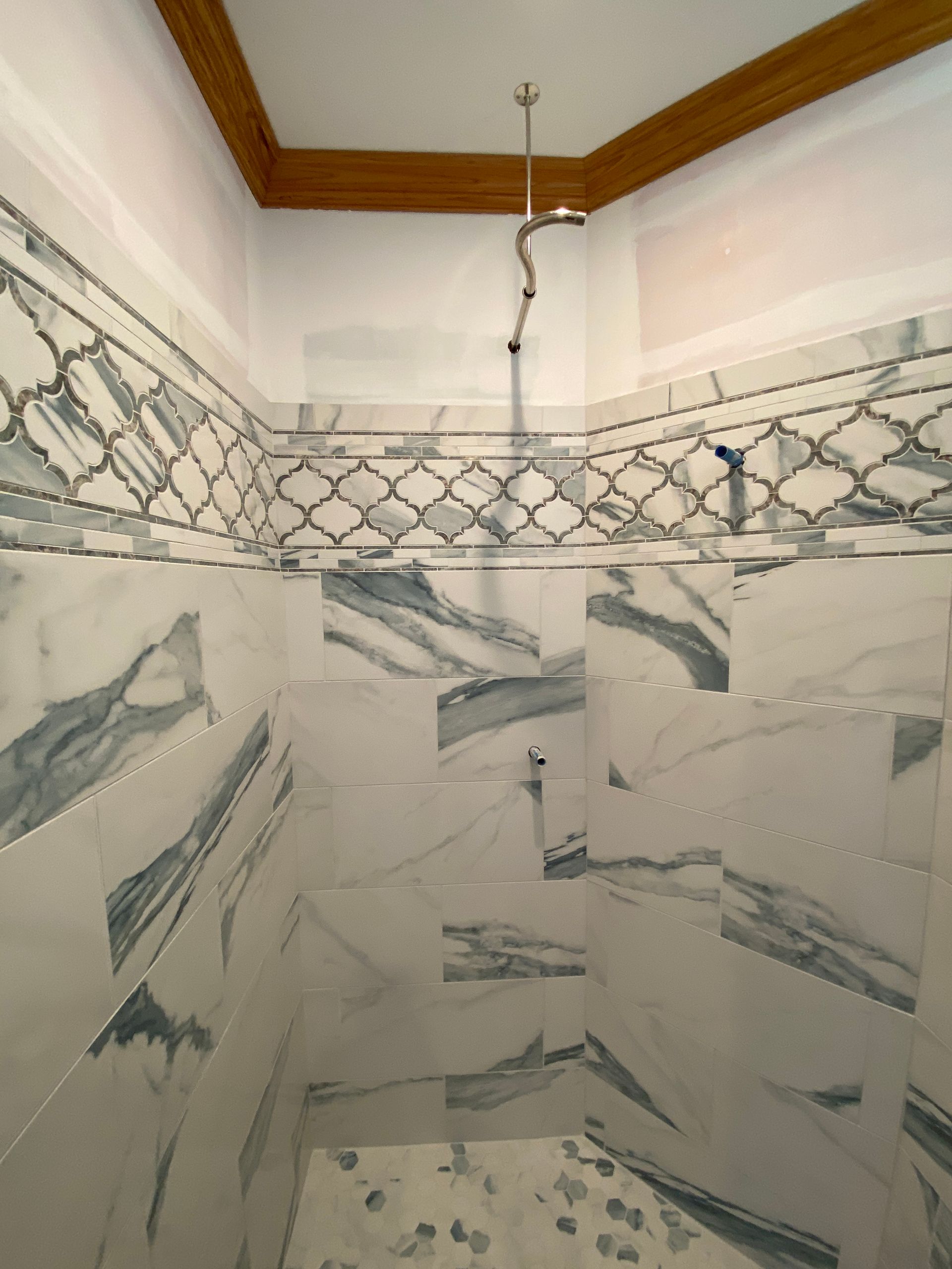 A shower with marble tiles and a shower head hanging from the ceiling