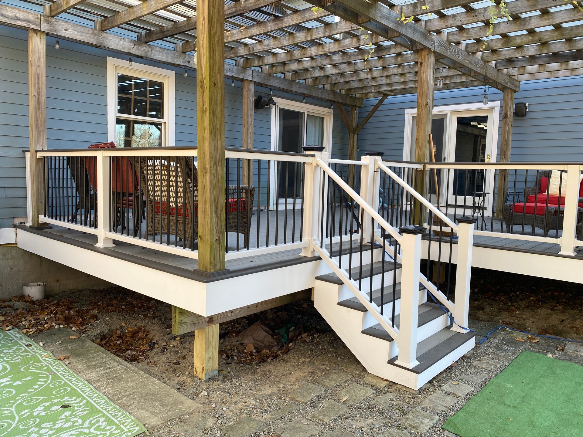 A deck with stairs and a pergola on top of it.