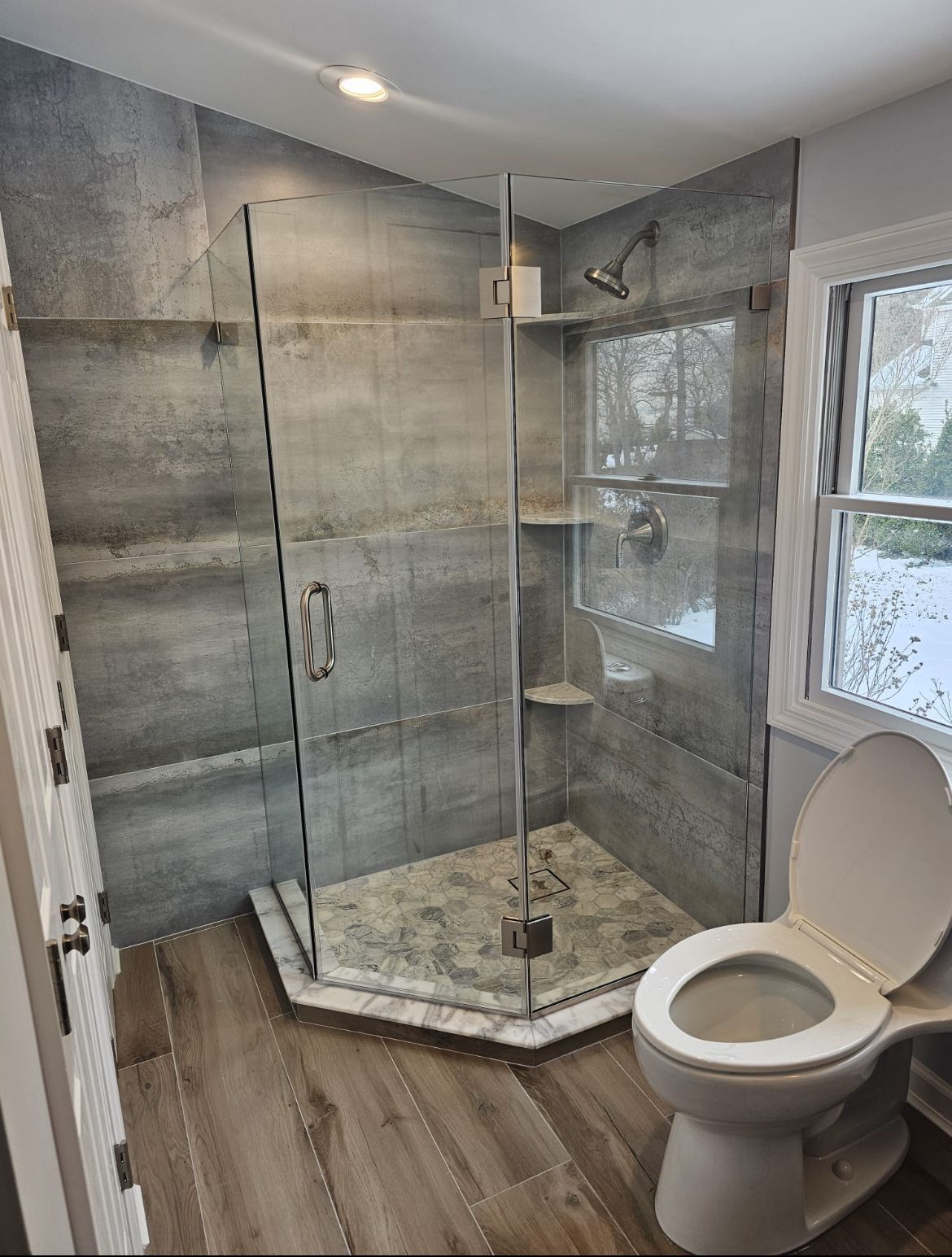 A bathroom with a toilet, shower, and window