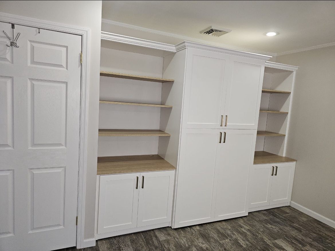 A bedroom with white cabinets and shelves and a door.