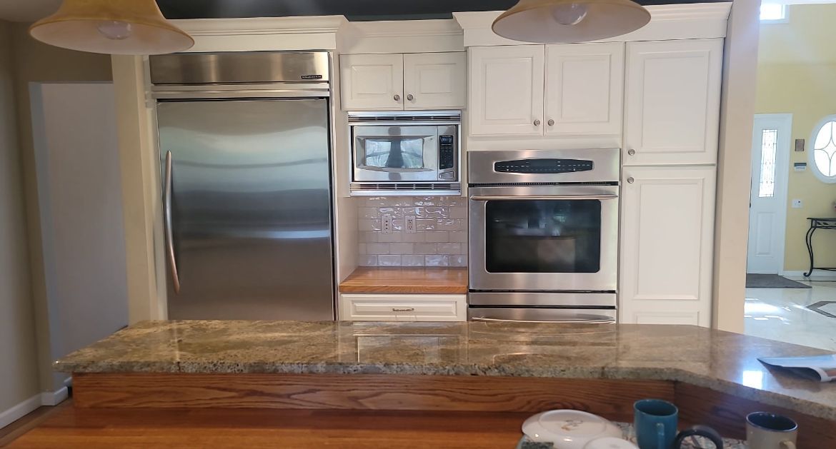 A kitchen with stainless steel appliances and white cabinets.