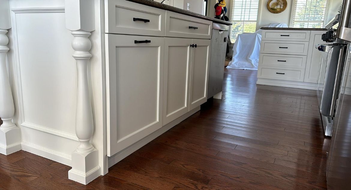A kitchen with white cabinets and hardwood floors
