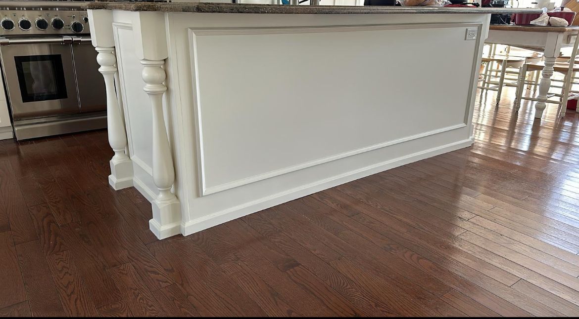 A white island in a kitchen with a wooden floor