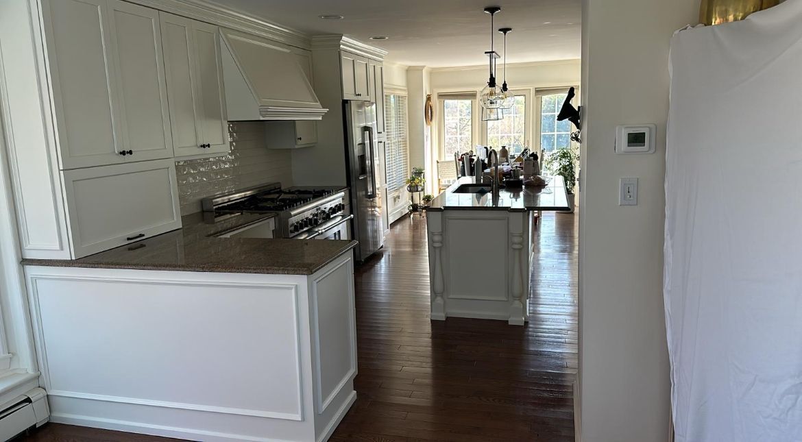A kitchen with white cabinets, granite counter tops, and a large island