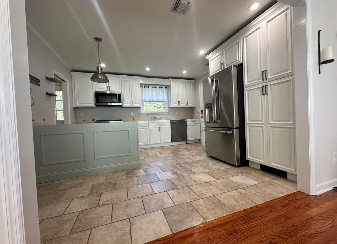 A kitchen with white cabinets and tile flooring