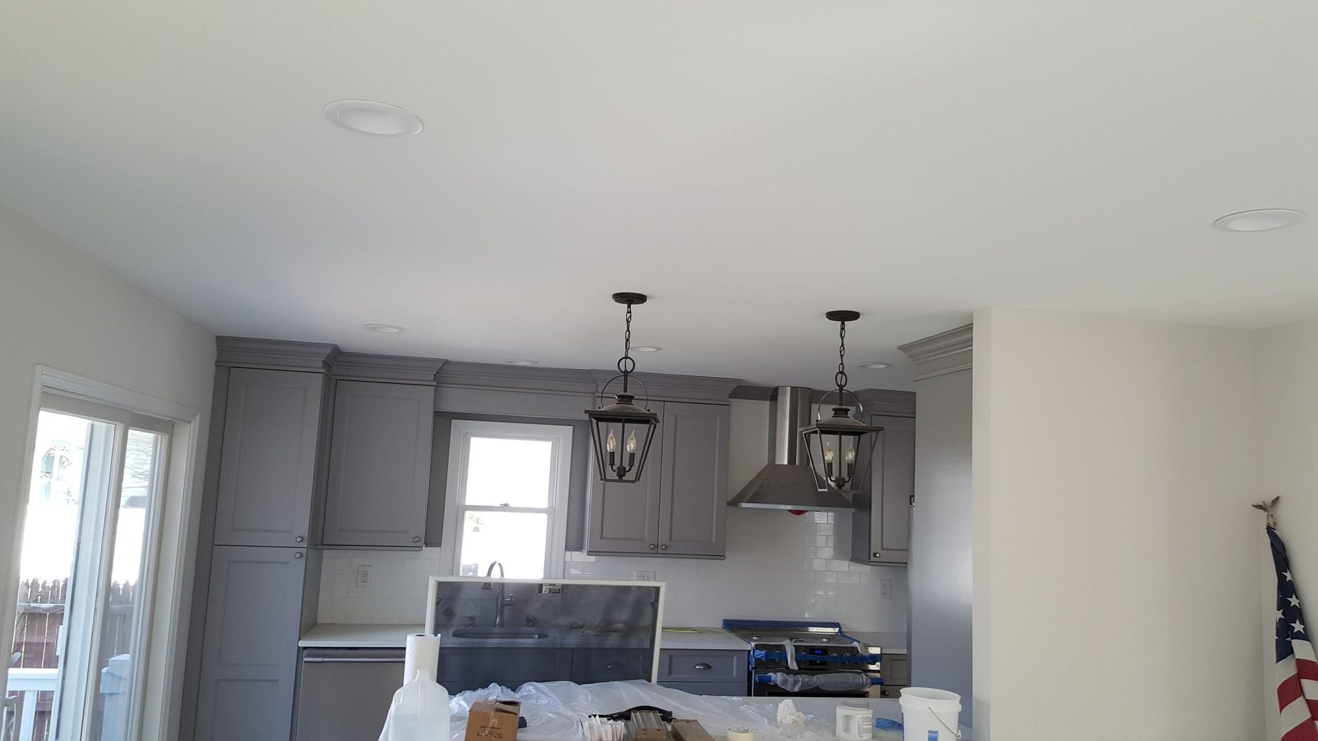 A kitchen with gray cabinets and white counter tops is being remodeled.