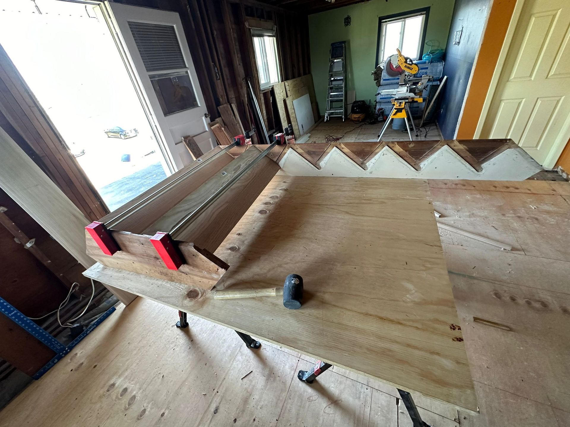 A wooden table with a hammer on it in a room.