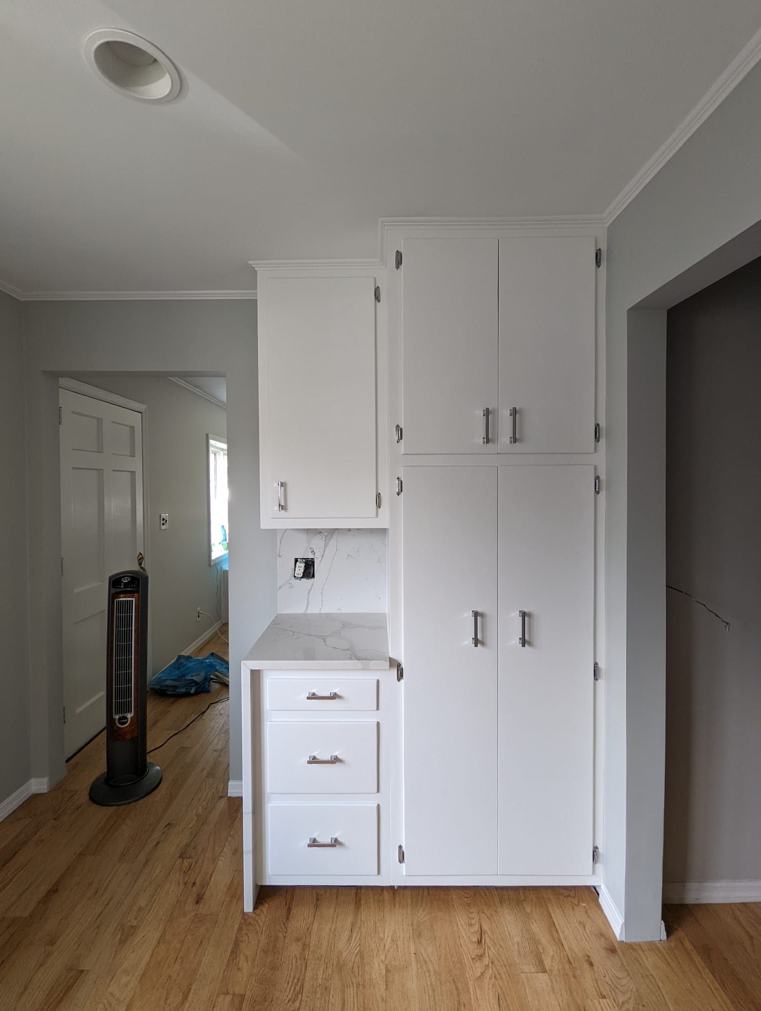 A kitchen with white cabinets and hardwood floors.