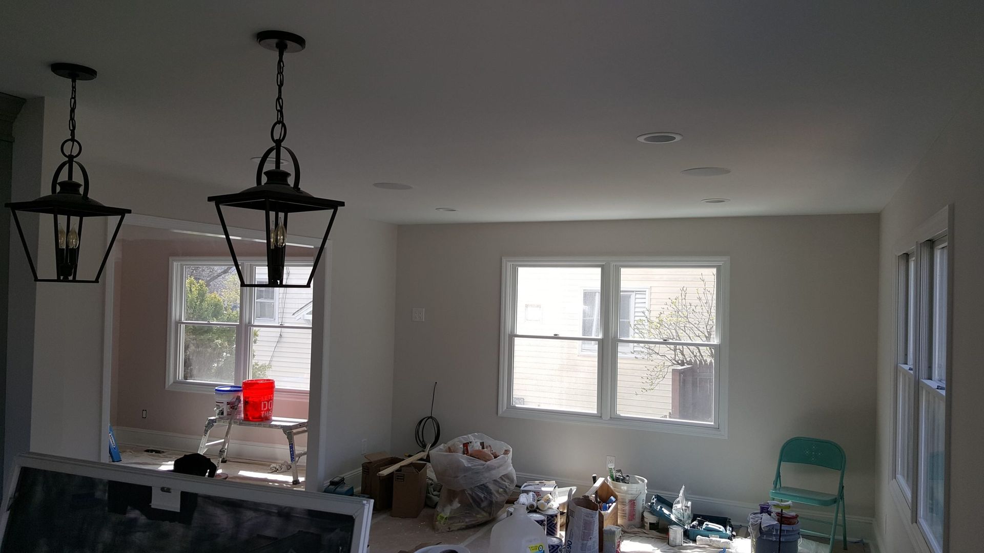A living room with a lot of windows and lamps hanging from the ceiling.