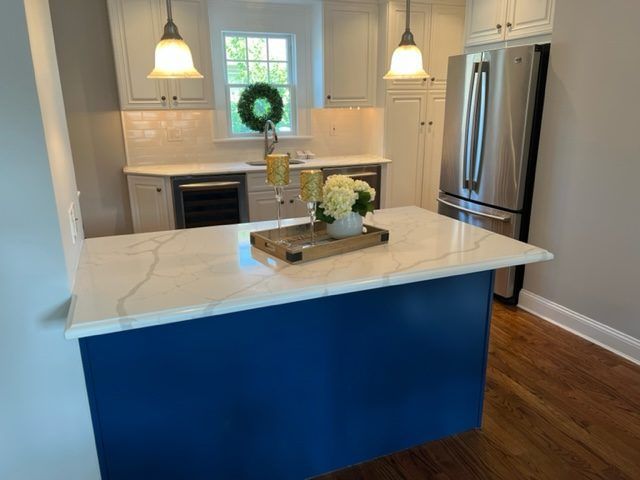 A kitchen with a blue island and a white counter top.
