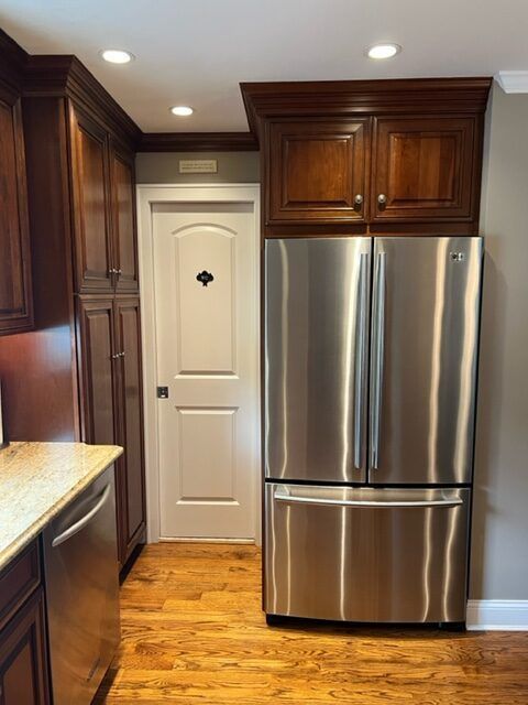 A kitchen with a stainless steel refrigerator and wooden cabinets