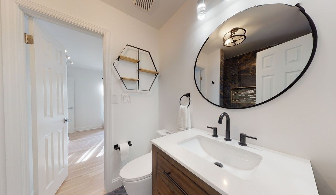 A bathroom with a sink, toilet and mirror.
