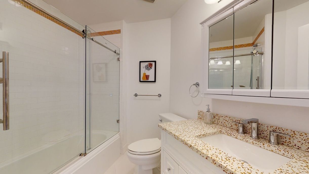 A bathroom with a toilet, sink, and shower.