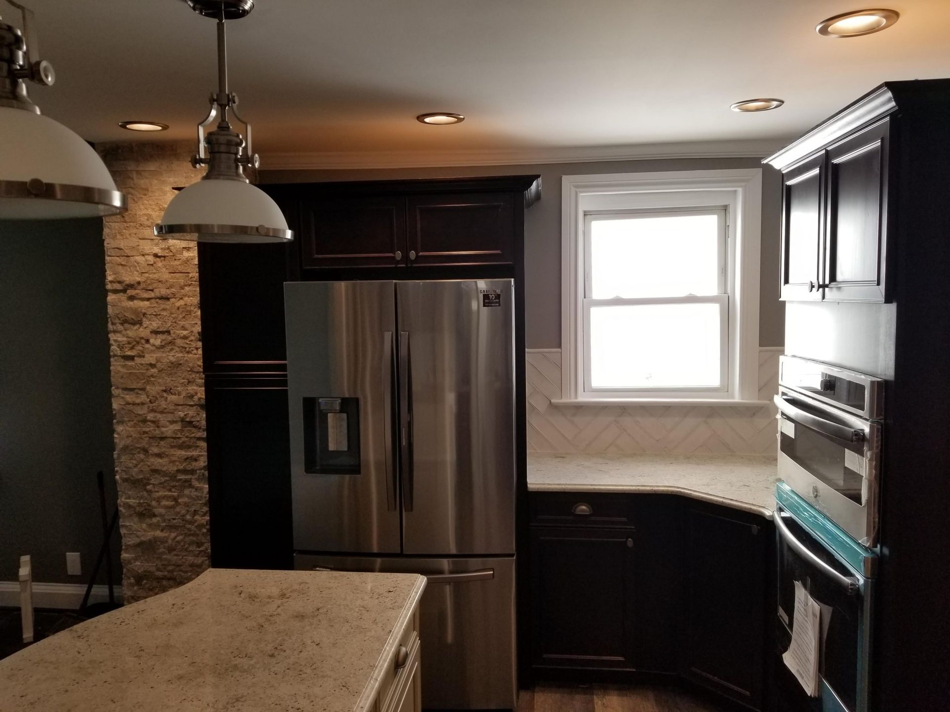 A kitchen with a stainless steel refrigerator and a window